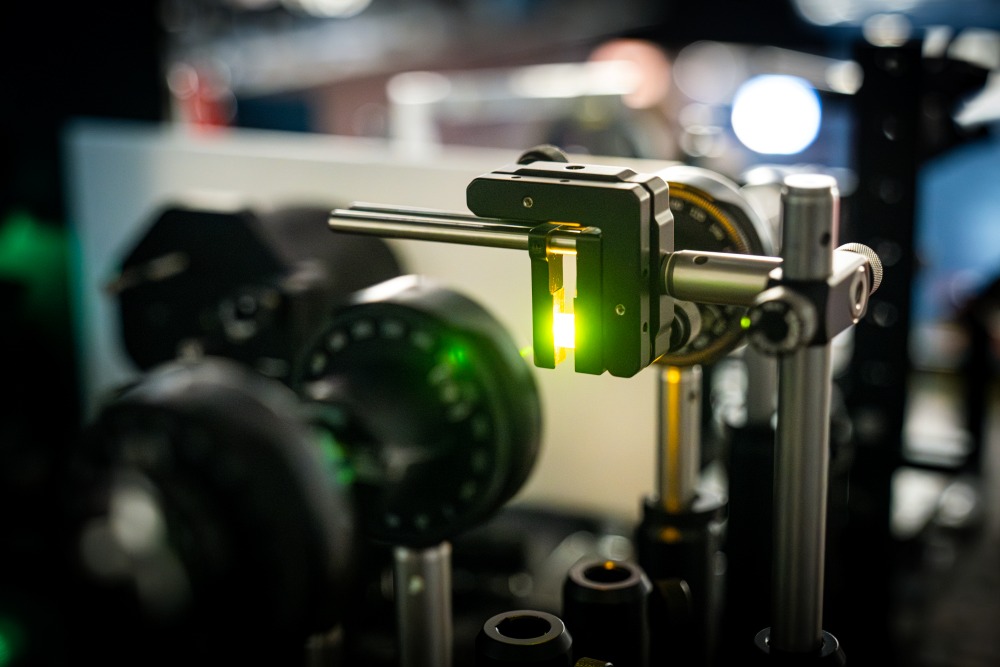 Examining a lead-halide perovskite crystal in the lab using optical methods. The sample glows green.